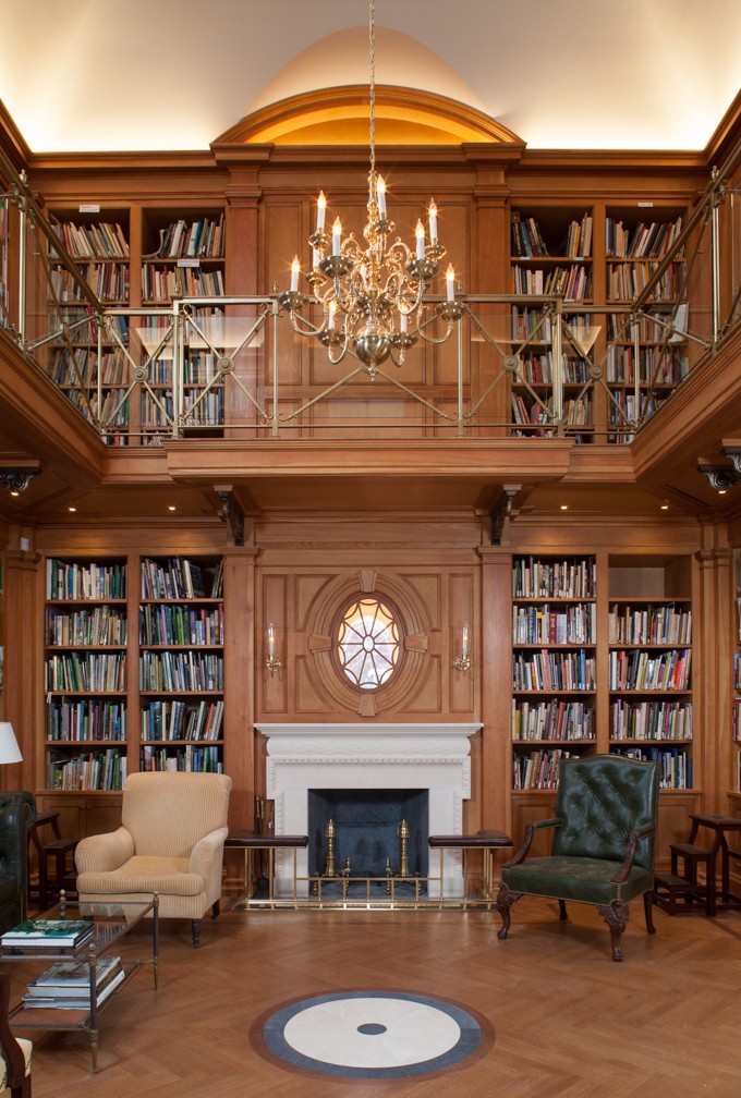 Double-height wood-panelled library at Bellevue House, with bookshelves, chandelier and fireplace.