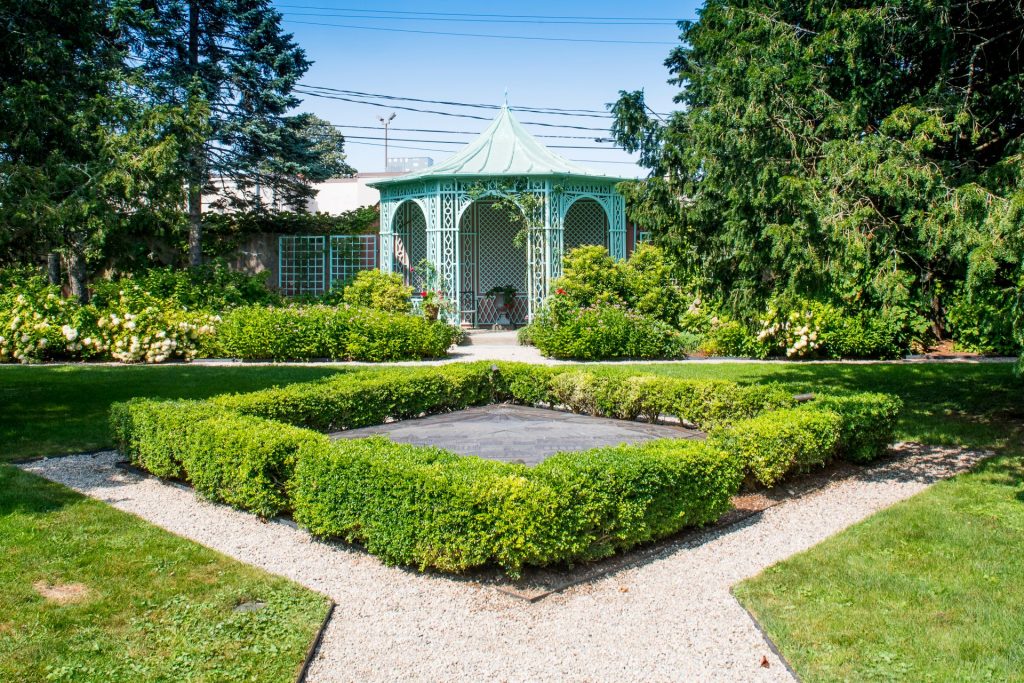 Pale green lattice gazebo framed by clipped hedges and a gravel path at Bellevue House.